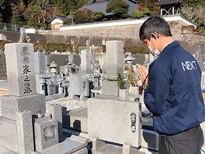 墓前で合掌するスタッフ