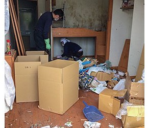 散らかった室内で作業する二人